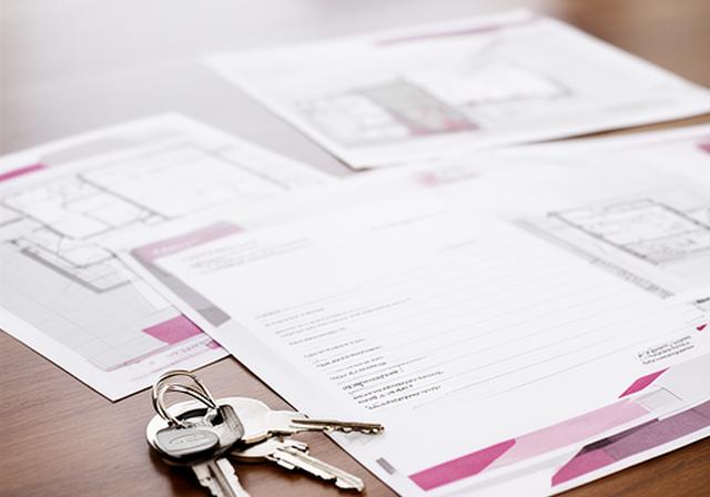 Contrato de arras junto a llaves de una vivienda y planos inmobiliarios en una mesa de reuniones